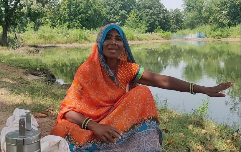 Farmer Dheema Rekbar shows the rainwater harvesting pond that helps her family grow crops.