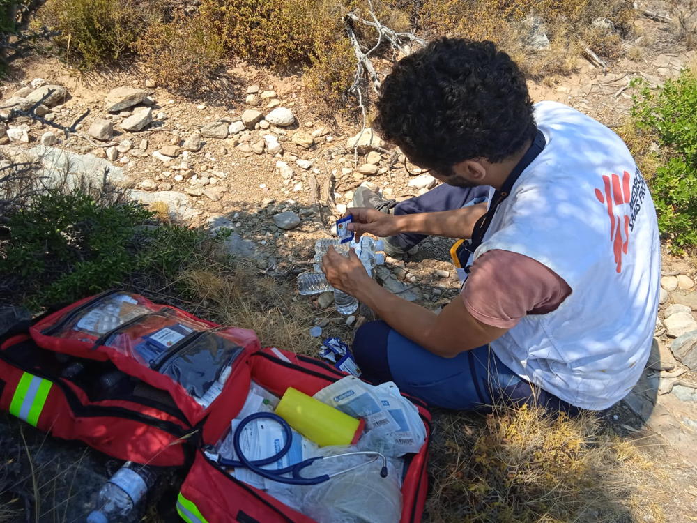Title: Emergency Medical Aid in Samos Copyright: MSF/Myrto Mouzaki Countries: Greece Date taken / Date Recorded: 28 August, 2023 Caption / Description: A MSF doctor is setting up his medical equipment in order to assist newly arrived asylum seekers during an Emergency Medical Assistance activity in Samos. Since 2021, MSF teams on Samos provide emergency medical care to people who arrive on the island by boat. Our support consists of medical and psychological first aid, including referrals to hospital by ambulance.