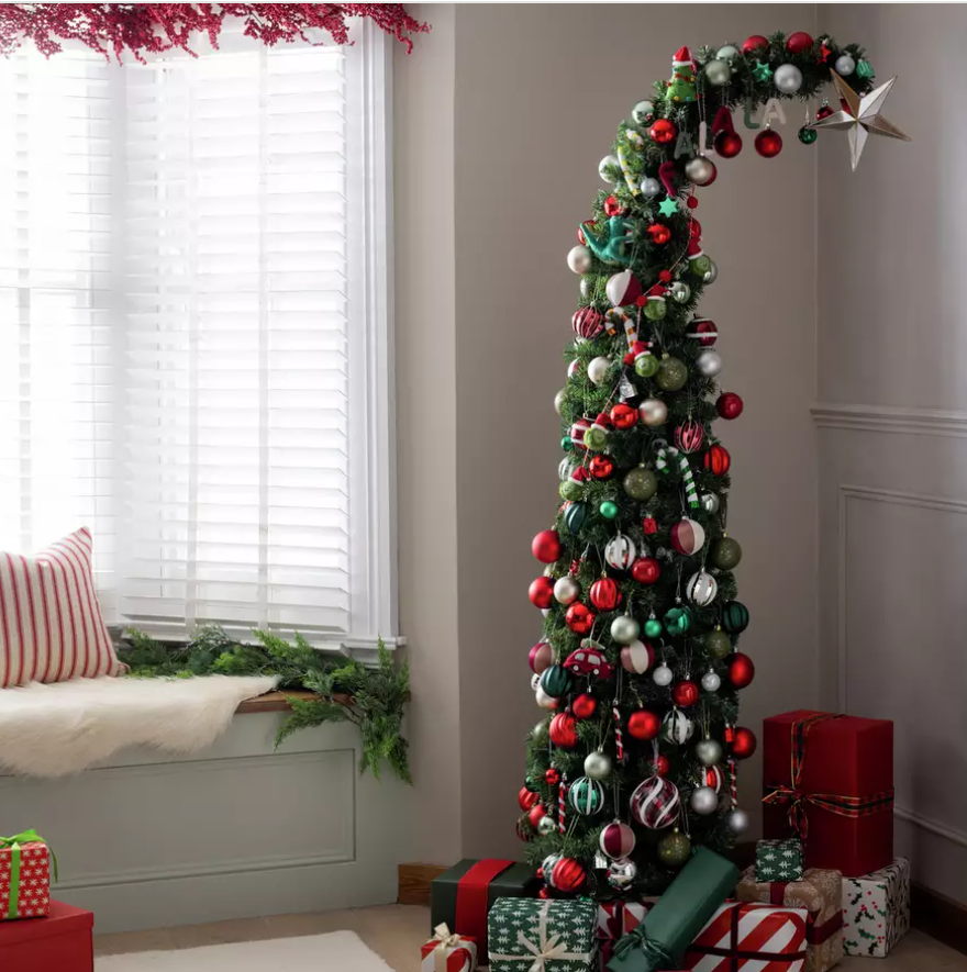 A christmas tree with presents in a corner of a room