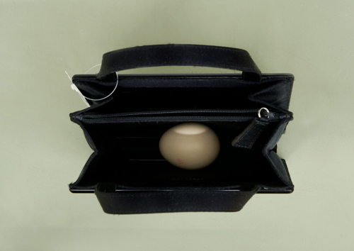 Income, 2023, Object at Gauli Zitter Brussels, image: Gauli Zitter Designer handbag bought at price of artist fee for a previous exhibition—kept by artist, sold as artwork or resold on online platform, barcoded sales label, hardboiled egg.