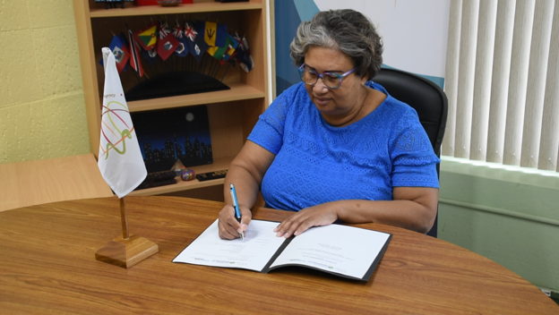 Dr. Joy St. John, Executive Director of the Caribbean Public Health Agency, affixing her signature to the partnership document for the Tourism Health Programme (THP).