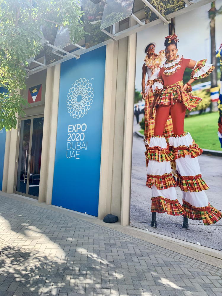 Cultural Stilt-walkers in National Wear grace the entrance of the Antigua and Barbuda pavilion
