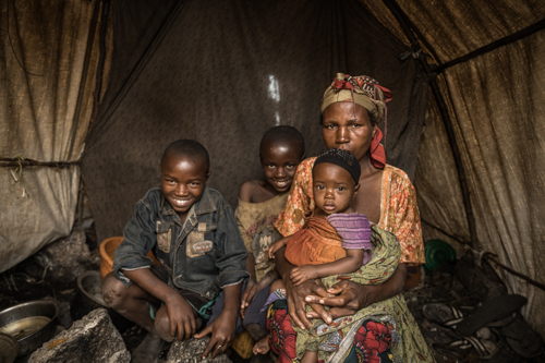 Portrait of Foibe Bonane with her three children inside their tent in Rusayo camp. Foibe Bonane is a 40 years-old woman from Tongo in the Masisi territory, who has been displaced for four months. Prior to that, she used to work as a bean and corn farmer in her native region. She decided to look for medical assistance when she noticed that one of her children had her eyes swollen when getting up from bed. After the consultation, the MSF team told her that the child is suffering from malnutrition combined with measles. Copyright - Michel Lunanga/MSF