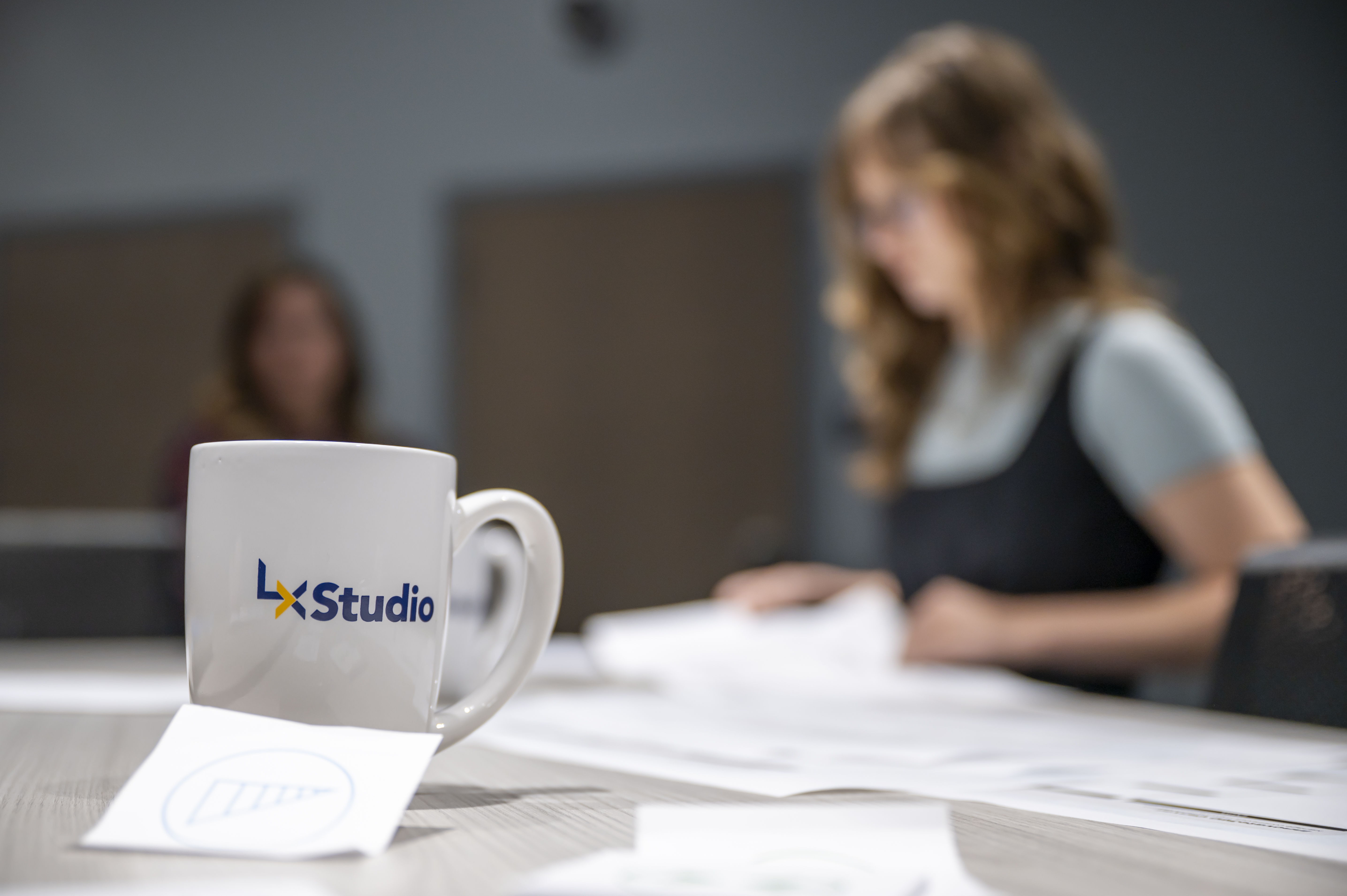 A coffee cup in the foreground with the LX Studio logo on it.