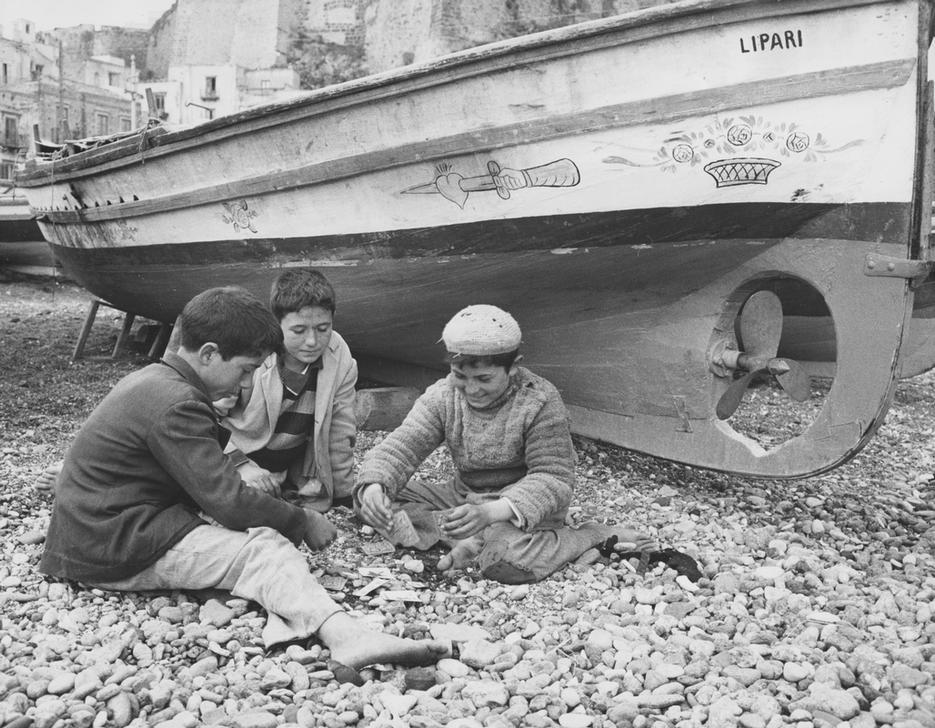 Sons of fishermen playing cards beside a boat. Island of Lipari, 1950s Lipari, Italy. AKG2414398 © akg-images / Mondadori Portfolio / Archivio Angelo Cozzi / Angelo Cozzi Sons of fishermen playing cards beside a boat. Island of Lipari, 1950s Lipari, Italy. AKG2414398 © akg-images / Mondadori Portfolio / Archivio Angelo Cozzi / Angelo Cozzi