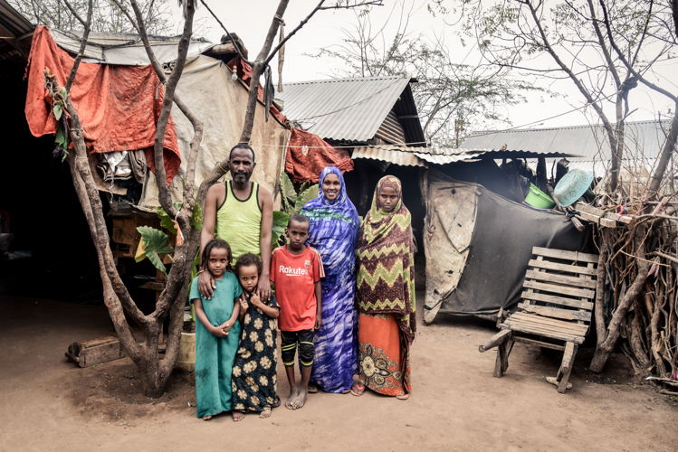 Abdo and his family in their home in Dagahaley camp. Abdo fled his country Ethiopia in 1997 due to political tensions, settling in Somalia. He stayed in Somalia until 2011. He met his wife, Muhaba Abdulrashid during his time there, and they sired four children. He was a farmer there but he says life became increasingly difficult there due to frequent fights, which sometime came even near his home. He fled Somalia in 2011 with his family, settling in Dagahaley camp. Since 2011, Abdo and his wife have sired four more children, all born in Dagahaley.
In Dagahaley, he does menial jobs to supplement the food rations provided by the World Food Programme (WFP) to sustain his family, which he says is difficult. “I usually fetch water from the tap stands, which I sell at the market, which yields me about Ksh 100/- (1 USD) on a good day,” he says.
He also fetches firewood on donkey carts, a process that often takes a week away from home, which he sells for Ksh 3,000/- (30 USD) at the market, mostly to hotels. Photographer: Paul Odongo Abdo and his family in their home in Dagahaley camp. Abdo fled his country Ethiopia in 1997 due to political tensions, settling in Somalia. He stayed in Somalia until 2011. He met his wife, Muhaba Abdulrashid during his time there, and they sired four children. He was a farmer there but he says life became increasingly difficult there due to frequent fights, which sometime came even near his home. He fled Somalia in 2011 with his family, settling in Dagahaley camp. Since 2011, Abdo and his wife have sired four more children, all born in Dagahaley.
In Dagahaley, he does menial jobs to supplement the food rations provided by the World Food Programme (WFP) to sustain his family, which he says is difficult. “I usually fetch water from the tap stands, which I sell at the market, which yields me about Ksh 100/- (1 USD) on a good day,” he says.
He also fetches firewood on donkey carts, a process that often takes a week away from home, which he sells for Ksh 3,000/- (30 USD) at the market, mostly to hotels. Photographer: Paul Odongo