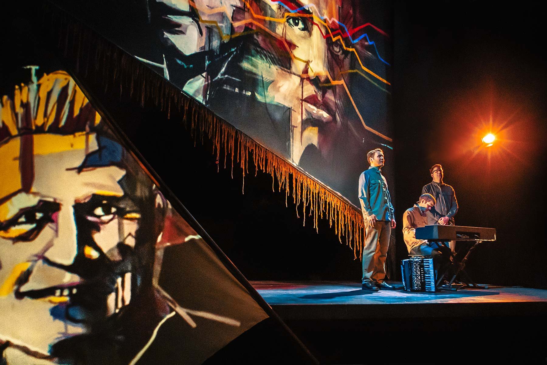 UK folk band The Young'uns performing The Ballad of Johnny Longstaff on stage in London's West End with colourful paintings of important people he meets in his life.