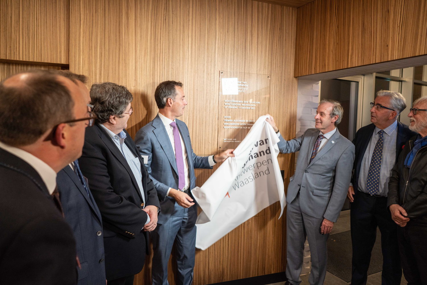 Federaal premier Alexander De Croo en burgemeester Lieven Dehandschutter van Sint-Niklaas onthullen samen de gedenkplaat in de inkomhal van de vernieuwde zetel-Waasland. 