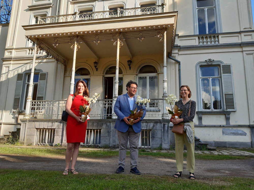 gedeputeerde An Vervliet, schepen van cultuur van Stad Gent Sami Souguir, en Donatienne Mertens de Wilmars, de laatste bewoonster, voor het kasteel Borluut met een orchidee van Orchideeën Petrens die ook aan bod komt in de Erfgoedsprokkel