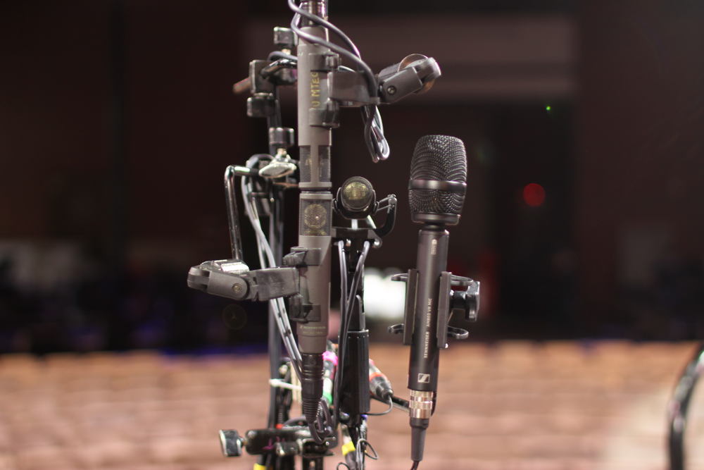The performance was staged with the conductor at the center, encircled by the audience and with the orchestra encircling them on the periphery. Three Sennheiser MKH 800 TWIN microphones and an AMBEO VR mic were placed at the center near to the conductor to capture a 3D audio image of the room.