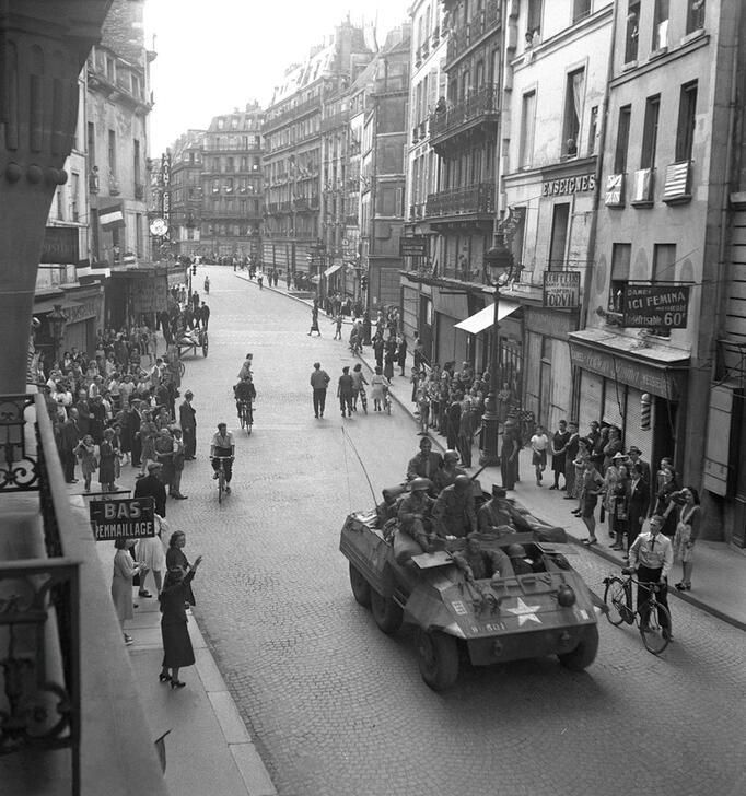 Parisians watch an American military vehicle go by. Rue du Four seen from a balcony at no. 25, looking towards Rue de Rennes at 5.25pm. AKG10792621 © René Zuber / akg-images