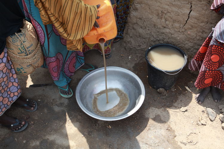 A woman pours out dirty water that has been scooped up from spillage at the borehole. She does this to demonstrate the low quality of water people have to wash themselves and their clothes with in Borno State (Pulka). Photographer: Scott Hamilton