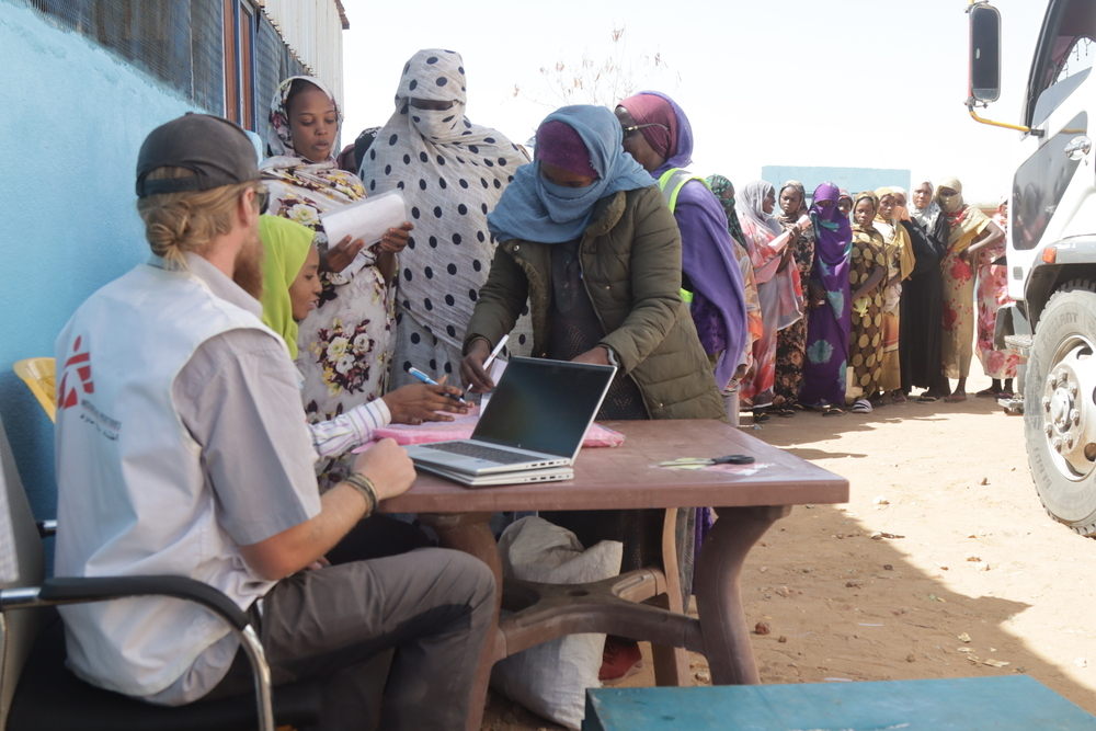 MSF is providing food to patients enrolled in its programmes and their families. Given the dire malnutrition situation demand for MSF’s food distribution programme far outweighs our capacity. Sadly this means we have to turn people away. Here an MSF staff member checks people are registered in our programmes before giving them a voucher to receive their food basket | Date taken: 05/01/2025 | Photographer: Abdoalsalam Abdallah | Location: Sudan