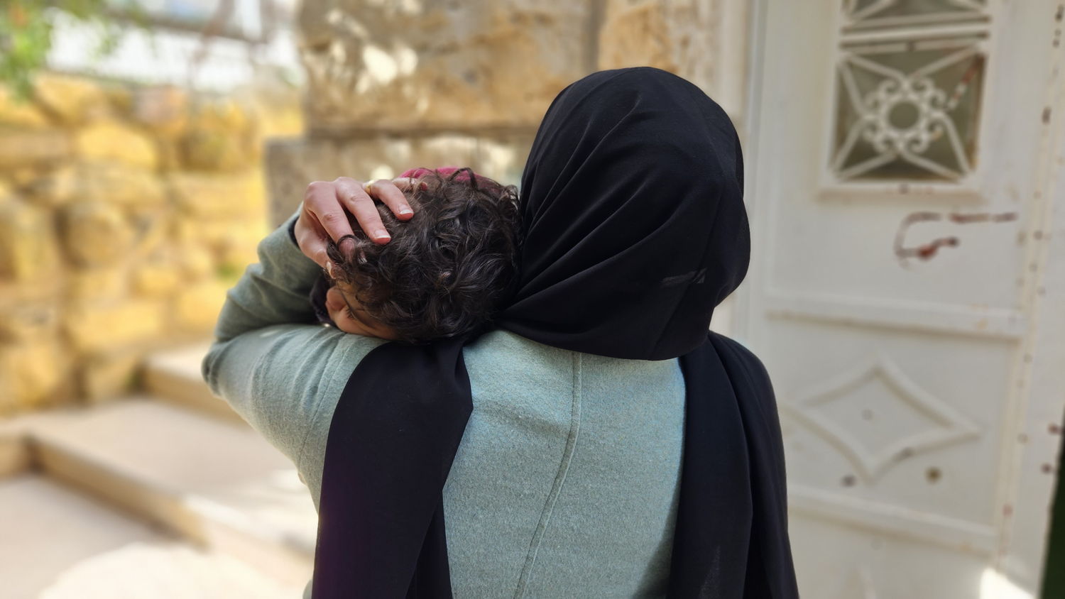 Aliyah*, a Palestinian woman holds tight her daughter in her arms. She lived for 25 years in the old city of Hebron, one of the most restricted areas within the West Bank, Occupied Palestinian Territories. Copyright: Laora Vigourt/MSF