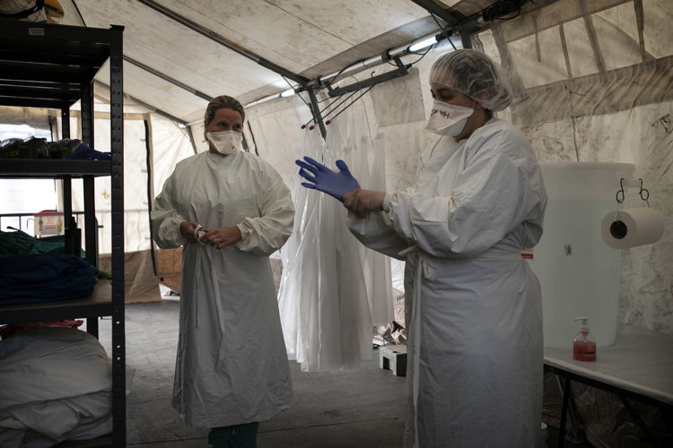 Julie (à gauche), ancienne infirmière de terrain MSF et maintenant volontaire dans le projet Covid-19 à Tour et Taxis, et Houria (promotrice de la santé MSF), s'habillent avec des équipements de protection avant d'entrer dans la zone des patients © Albert Masias / MSF