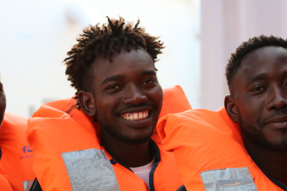 Rescued people smile as the MSF and SOS MEDITERRANEE prepare them to be transferred to the Armed Forces of Malta for disembarkation in Malta. Photographer Hannah Wallace Bowman Location Med Sea  24082019 
