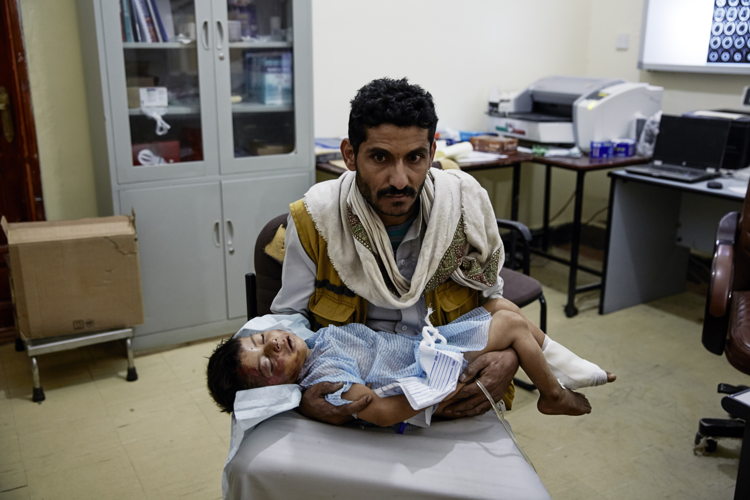 Un père tient son enfant blessé dans une structure de santé de Sana'a au Yémen en 2015 © MSF