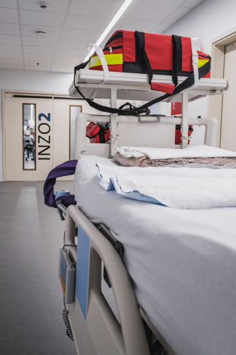 Een high care bed met de nodige uitrusting  voor transport: monitor, transportdefibrillator, zuurstoffles, spuitpompen. 