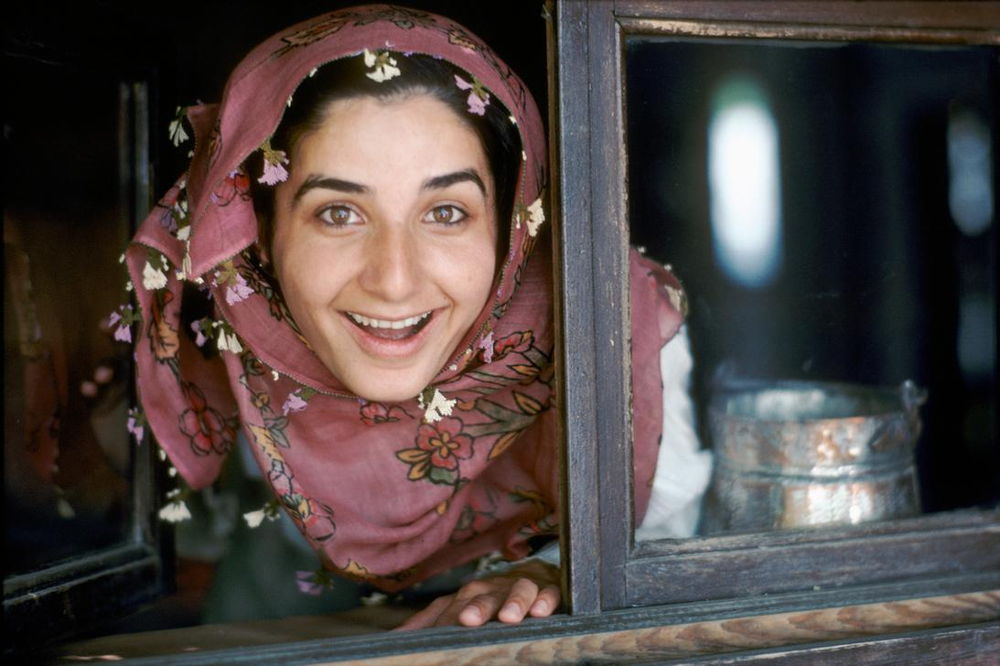 Portrait of a smiling young woman looking out of a window, Turkey, 1986. AKG2267923
