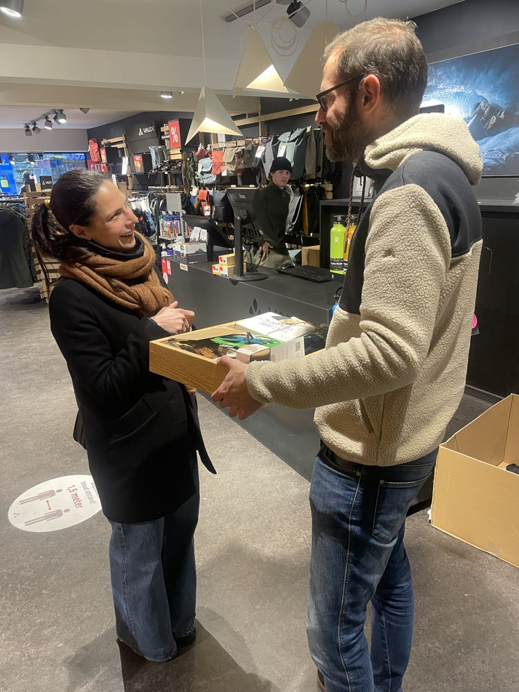 Schepen Lalynn Wadera gaf een cadeau (gemaakt door People Made) aan Roel,  medewerker van Vaude, de winkel die het 10.000ste pakketje via wij.leveren verstuurde. 