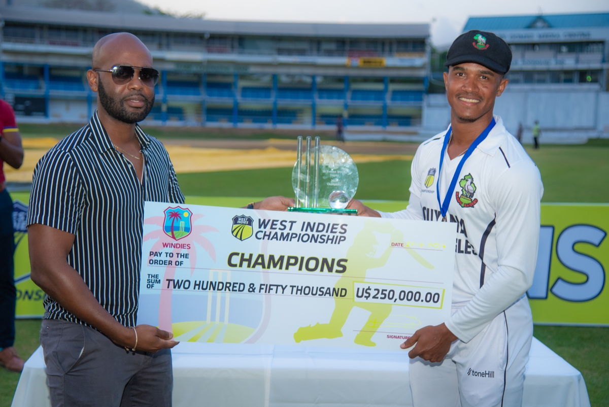 President Dr. Kishore Shallow presenting the $250,000 USD champions cheque to Tevin Imlach. 