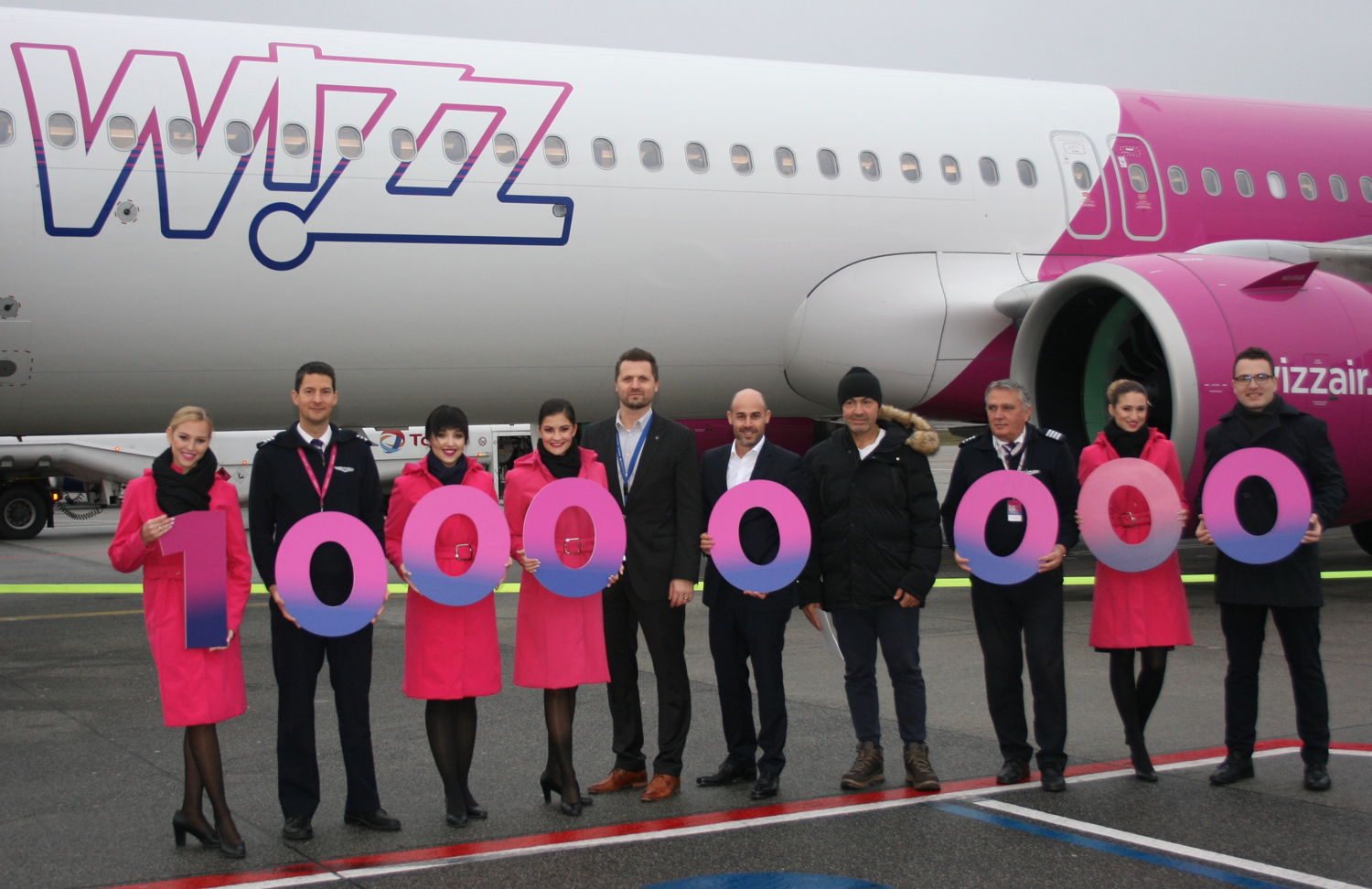 Dean Boljunovic, Head of Route Development van Eindhoven Airport, Andras Rado, Corporate Communications Manager van Wizz Air, en de 10 miljoenste passagier op de WIZZ-routes van en naar Eindhoven, omringd door de volledige crew van de Budapest-vlucht van vanochtend.