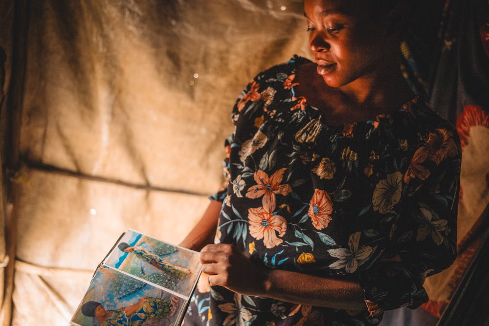 Alice Feza, 19 ans, originaire de Buhumba dans le territoire de Nyiragongo, regarde son album photo dans sa tente, le seul objet qu'elle a pu emporter dans sa fuite. Site de personnes déplacées à Kanyaruchinya, au nord de Goma, Nord-Kivu, République démocratique du Congo, 4 janvier 2024. Copyright: Philémon Barbier Alice Feza, 19 ans, originaire de Buhumba dans le territoire de Nyiragongo, regarde son album photo dans sa tente, le seul objet qu'elle a pu emporter dans sa fuite. Site de personnes déplacées à Kanyaruchinya, au nord de Goma, Nord-Kivu, République démocratique du Congo, 4 janvier 2024. Copyright: Philémon Barbier