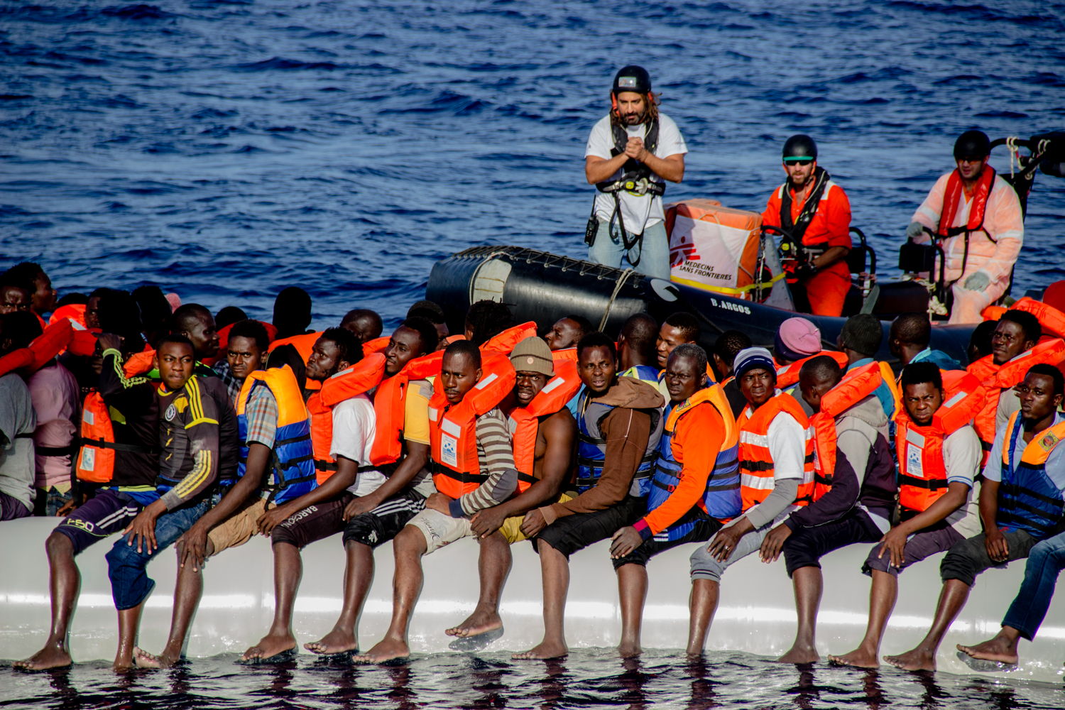 Firas Hebili van Artsen Zonder Grenzen kalmeert vluchtelingen in een rubberboot op de Middellandse Zee tijdens een reddingsoperatie. Om de redding goed te laten verlopen, is het cruciaal dat iedereen zo rustig mogelijk blijft ©Borja Ruiz