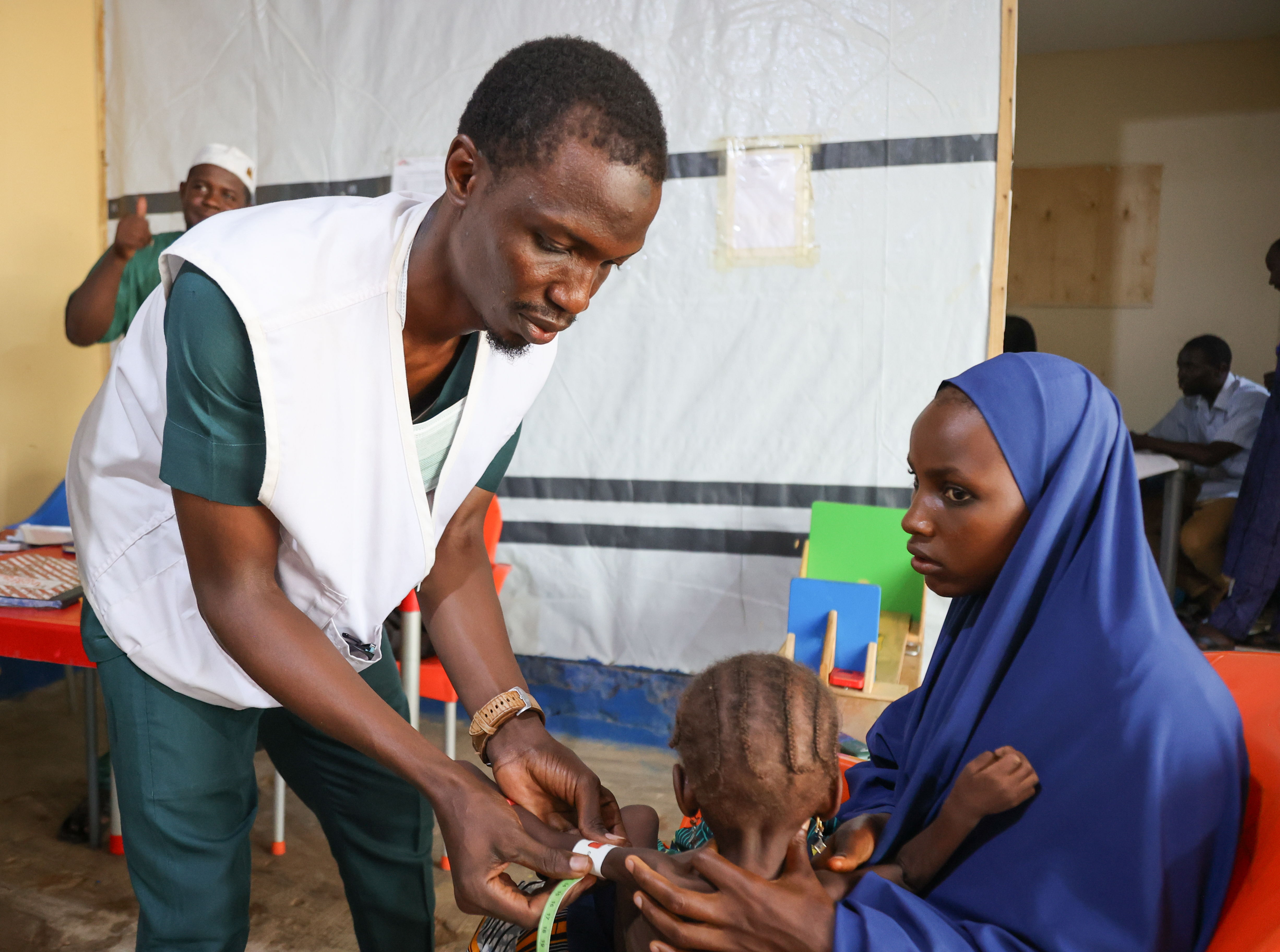 Muhammad Faysal Abdullahi, asistente de enfermería de MSF, mide el perímetro del brazo de un niño para saber si está desnutrido. Foto: Miguel Godonou/MSF.