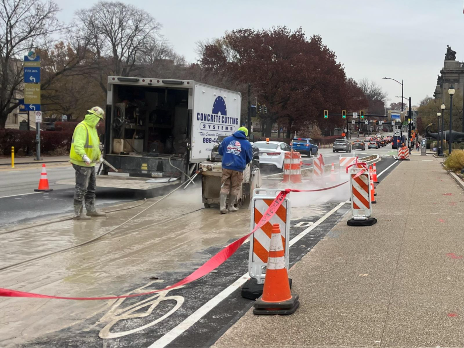 Crews saw-cutting concrete sidewalk on Forbes Avenue between Schenley Drive and Schenley Drive Extension
