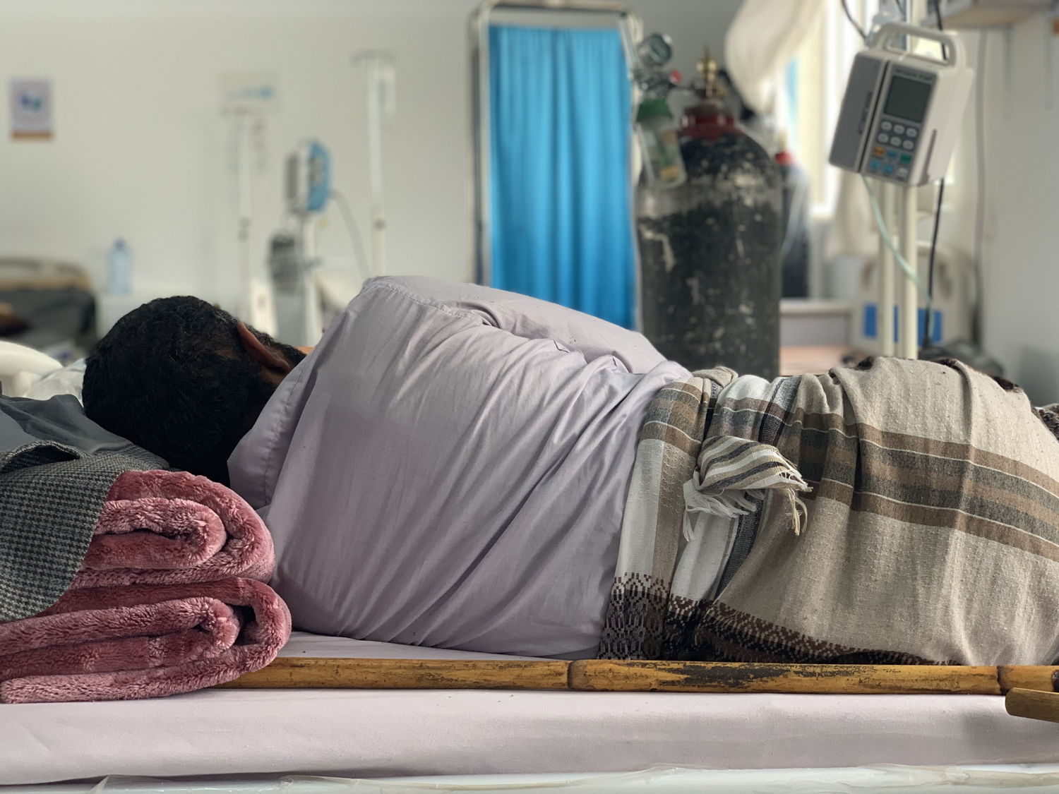 A patient receiving treatment lying in the male IPD room of the MSF-supported Sheikh Zayed COVID-19 centre in Sana’a. Copyright: Maya Abu Ata
