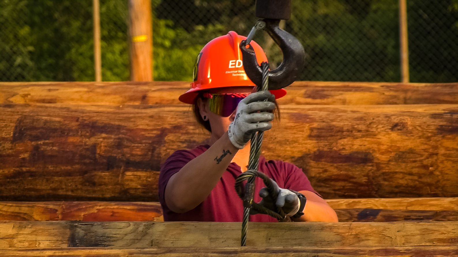 EDT apprentice Lexie Nowakowski secures a utility pole to a hook in preparation for lifting onto a truck for transport. (Nick Ruffolo)