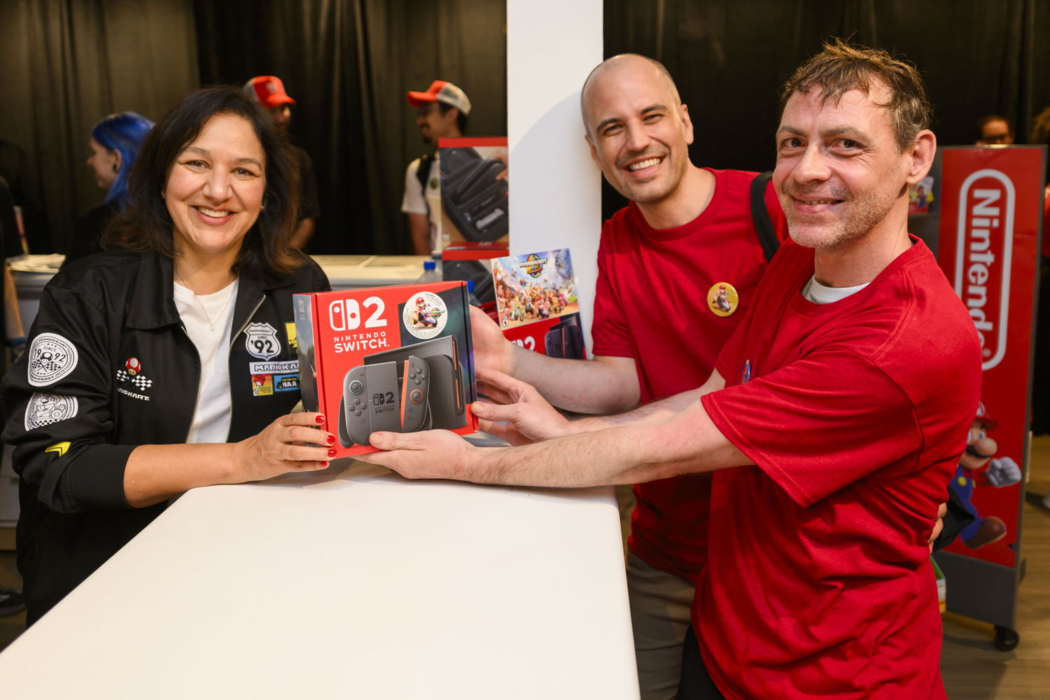 In this photo provided by Nintendo of Canada, Nintendo of Canada’s VP and General Manager, Susan Pennefather, hands the first Nintendo Switch 2 system sold to a pair of excited fans