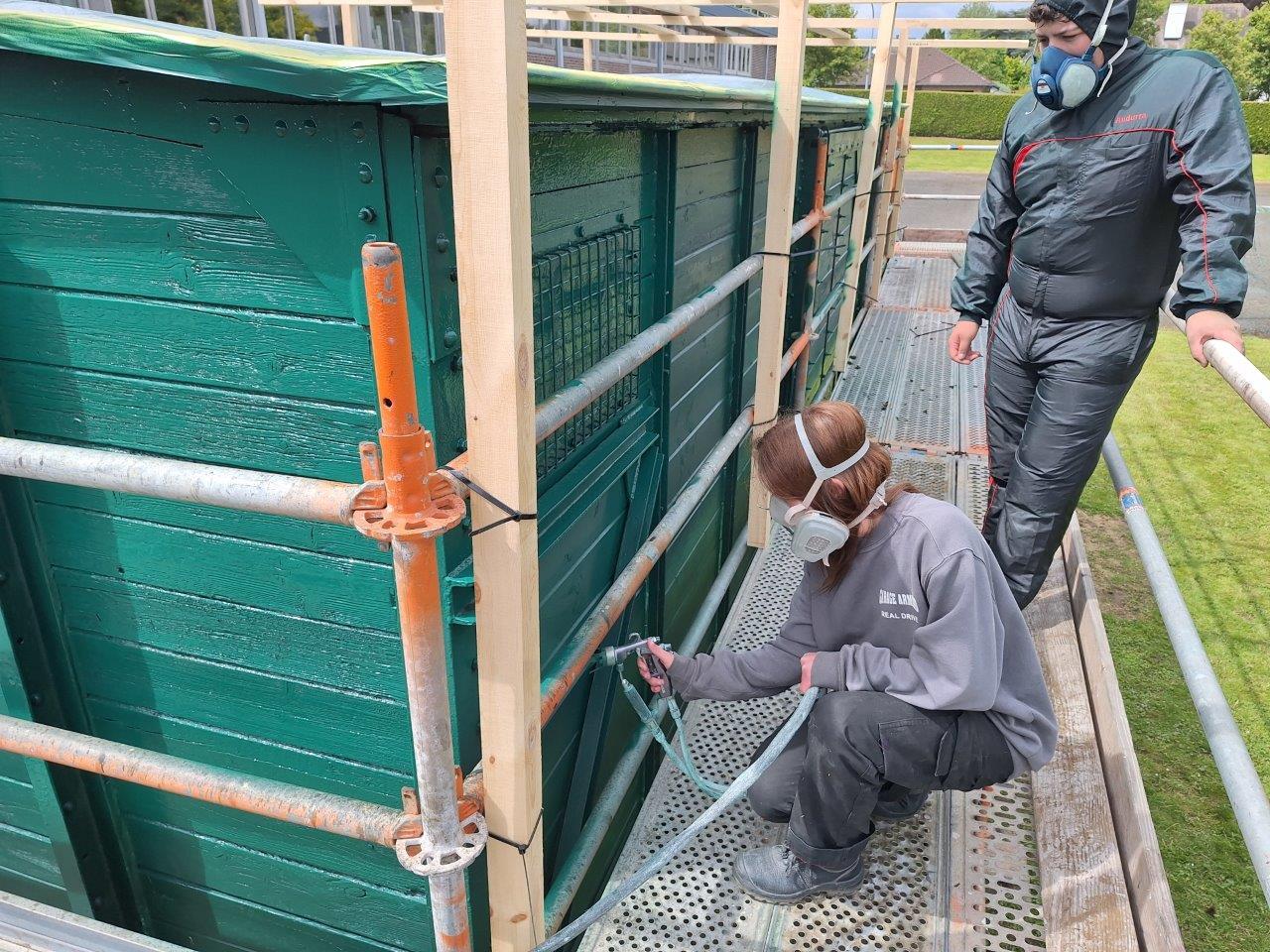 actiefoto restauratie in Richtpunt Zottegem verven wagon door meisje uit richting Koetswerk in originele groene kleur