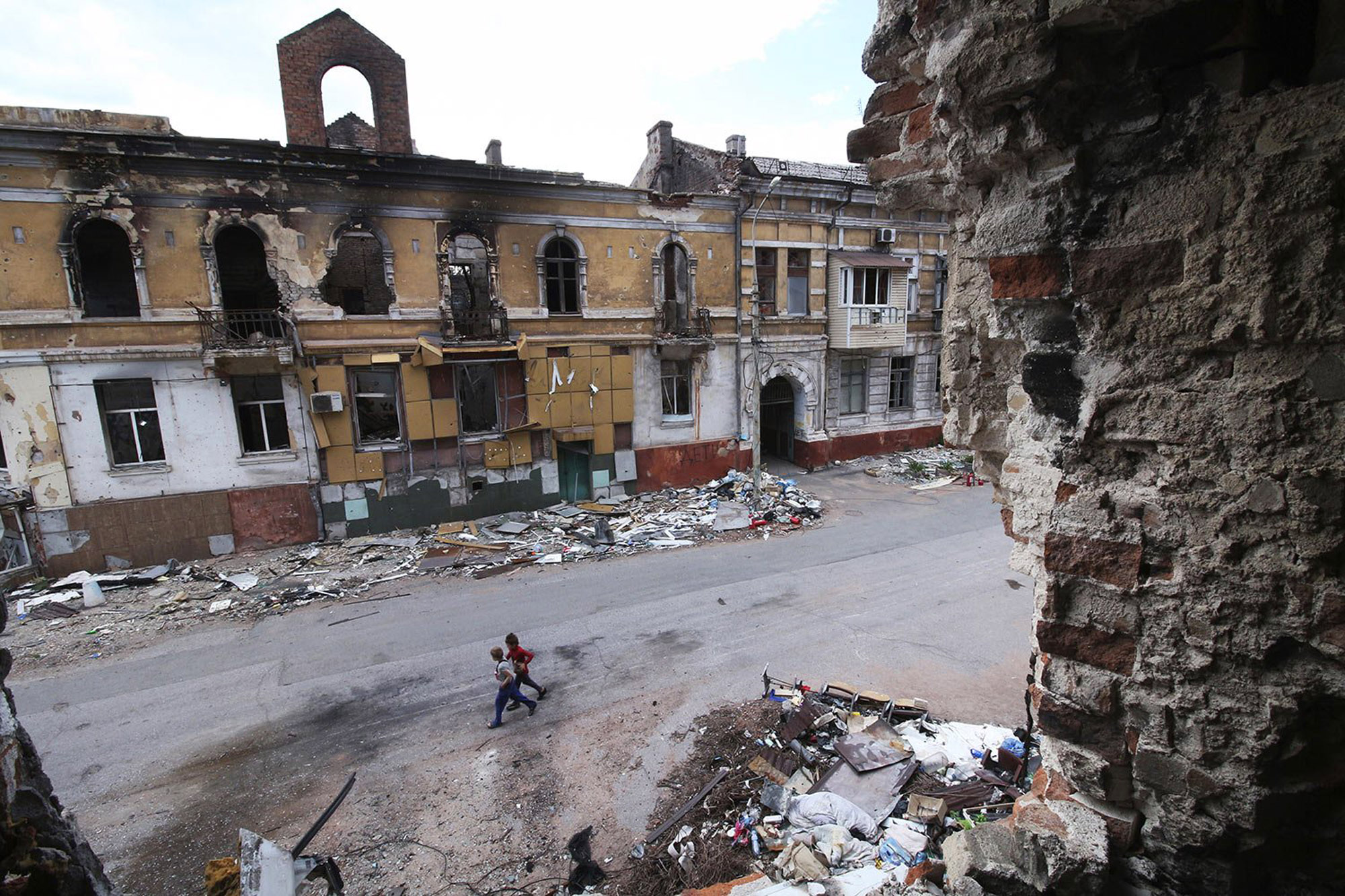 Children walk amid destroyed buildings in Mariupol which is under Russian control in eastern Ukraine, Wednesday, May 25, 2022. (AP Photo)