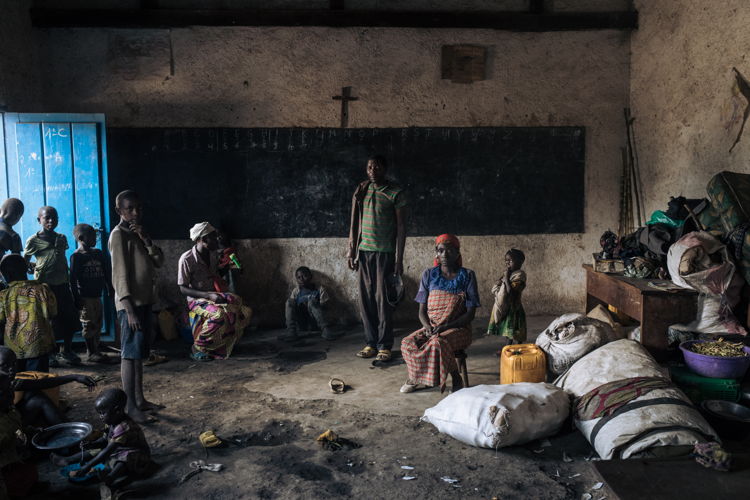 Title: North Kivu: displaced communities are losing hope as M23 crisis drags on Copyright: Alexis Huguet Countries: Democratic Republic of Congo Date taken / Date Recorded: 13 July, 2022 Caption / Description: Displaced people, including children, stand in the classroom of Rumangabo elementary school, which in recent weeks has been transformed into an IDP site that hosts more than 3,000 people, on July 15, 2022, in North Kivu province, eastern Democratic Republic of Congo. The front line between the Congolese army and the M23 armed group is just a few miles from the village.