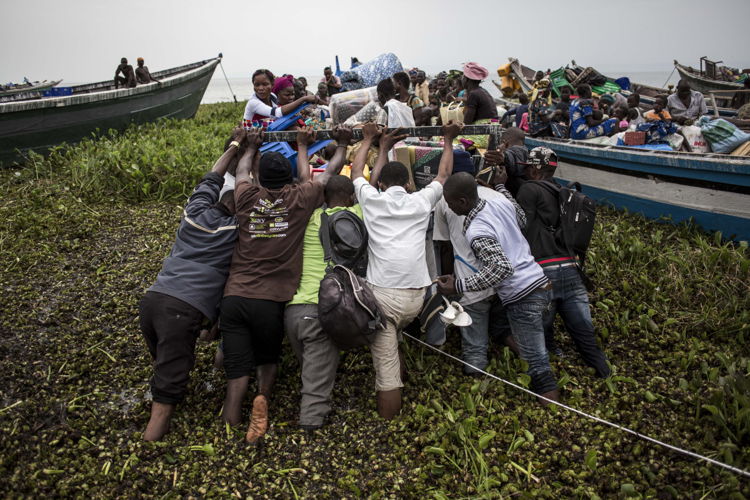 On 5 March 2018, internally displaced Congolese push a boat into Lake Albert. It will will take them to the relative safety of Uganda. The town of Tchomia is the one of the main towns for thousands of Congolese IDPs to flee to refugee camps on the shores of Lake Albert in Uganda. After the cholera outbreak in the refugee camps in Uganda, there is a fear of a subsequent outbreak in Tchomia, which would affect thousands of IDPs taking refuge along the shoreline of Lake Albert in DRC. PHOTO/JOHN WESSELS