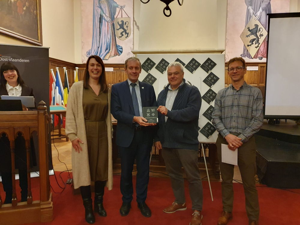 Overhandiging van de gedenkplaat aan het stadsbestuur van Sint-Niklaas (gedeputeerde An Vervliet, Burgemeester Lieven Dehandschutter, Schepen Filip Baeyens en Filip Kint van Monumentenwacht Oost-Vlaanderen)
