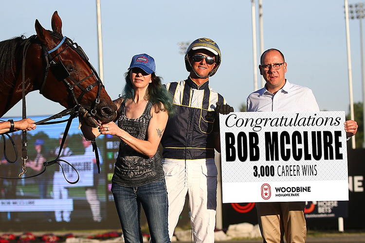 Bob McClure receives a sign recognizing his 3,000th win from Bill McLinchey, Director of Standardbred Racing. (New Image Media)