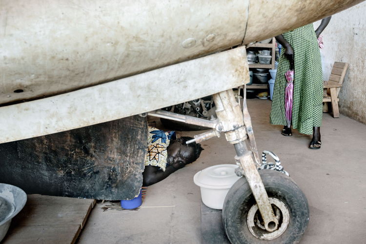 A woman sleeping on the floor underneath an old airplane in Mpoko camp, next to Bangui airport. During the day, some people return to the neighbourhood where they live, but they are too afraid to stay there at night so they then return to the camps. A woman sleeping on the floor underneath an old airplane in Mpoko camp, next to Bangui airport. During the day, some people return to the neighbourhood where they live, but they are too afraid to stay there at night so they then return to the camps.