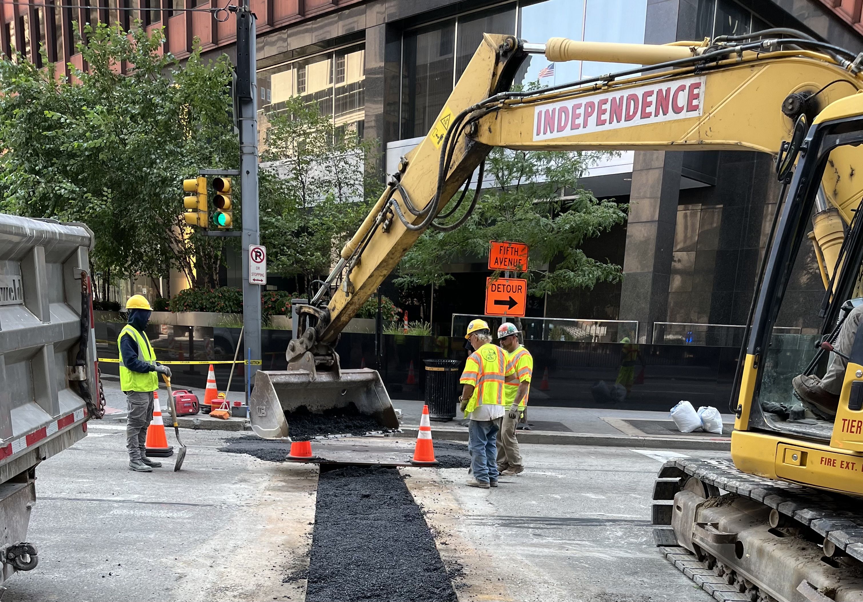 Electrical crews placed temporary asphalt on Liberty Avenue after running conduit underneath the roadway that will supply power to the new bus shelter