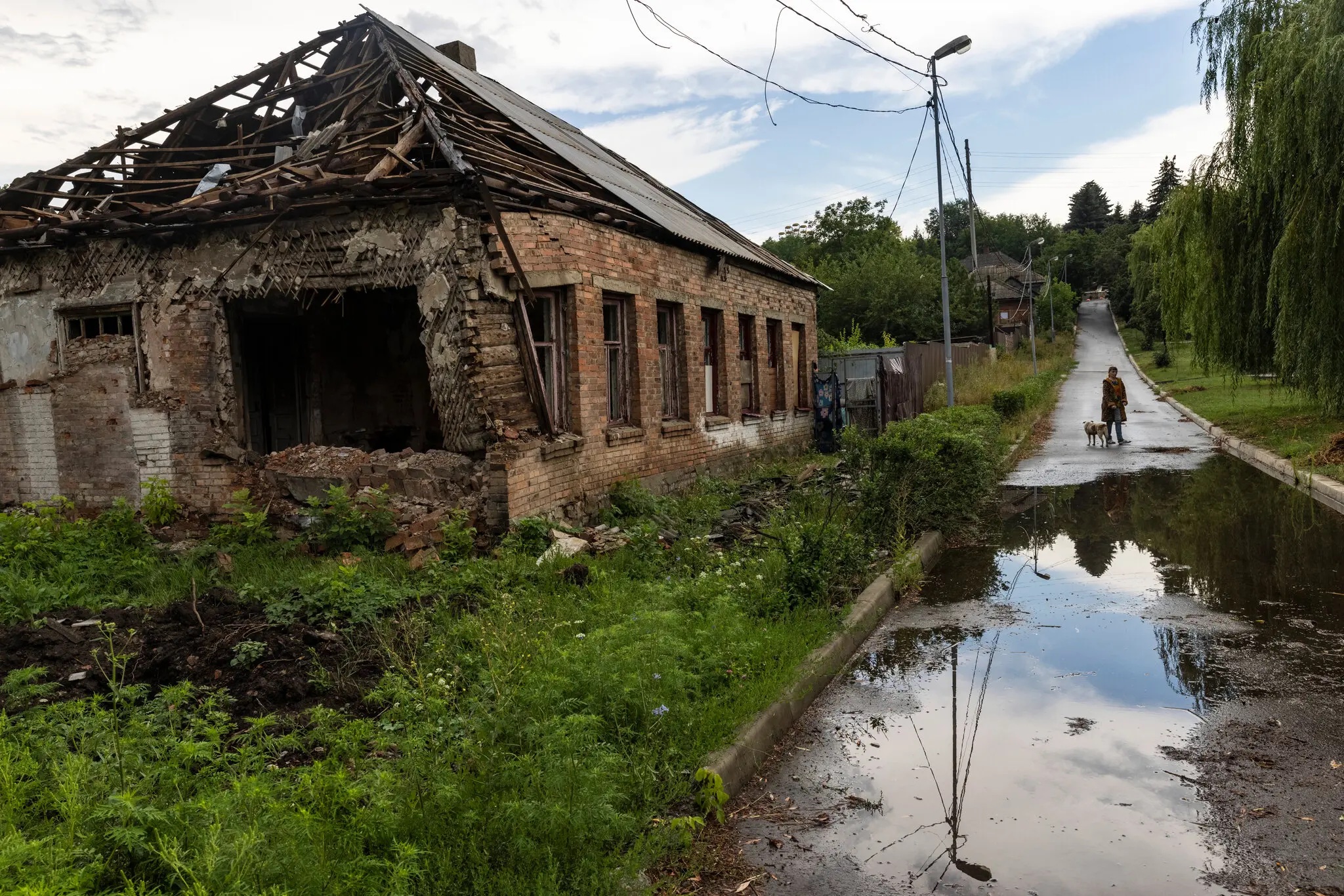 A Ukrainian citizen stands in front of her family’s home which was destroyed by Russian rockets, in the Ukrainian frontline town of Bakhmut, on Aug. 2. Image courtesy of David Guttenfelder, The New York Times 