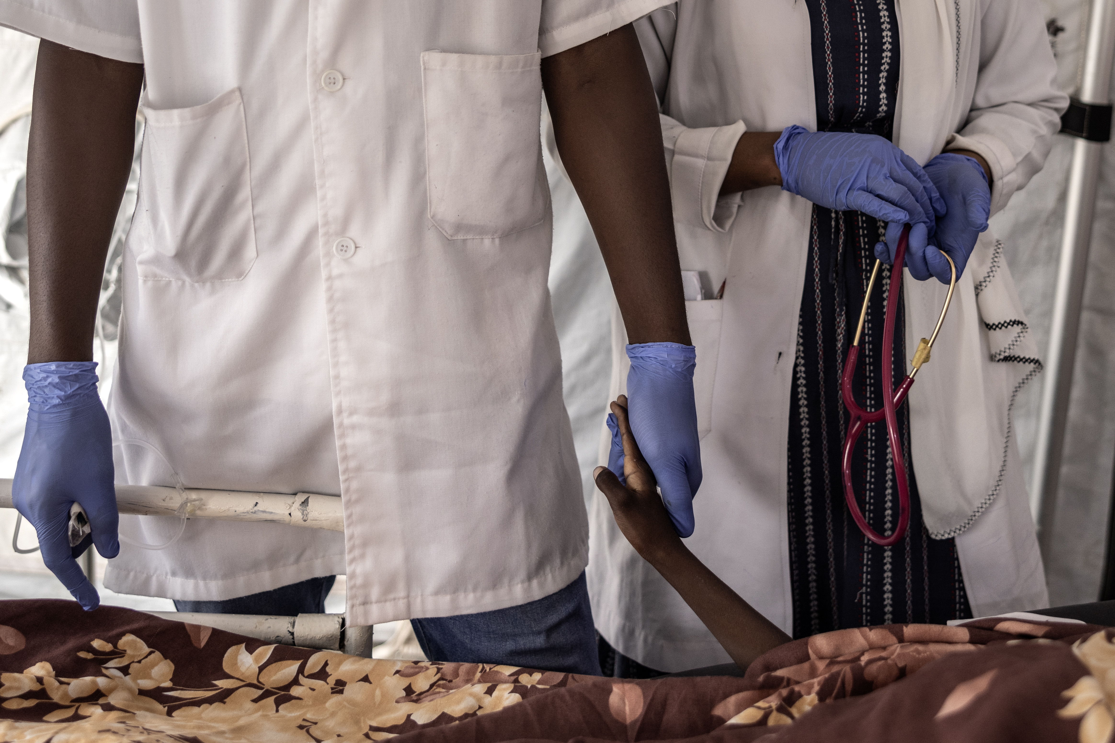 Een verpleegkundige houdt de hand vast van de 10-jarige Haidara Atim, nadat hij overleed toen artsen hem niet konden reanimeren op de intensive care van het AZG-ziekenhuis in Metche, in het oosten van Tsjaad, 7 augustus 2024. In kamp Metche verblijven ongeveer 40.000 Soedanese vluchtelingen die het geweld in Darfur zijn ontvlucht. Finbarr O'Reilly/VII Foto.