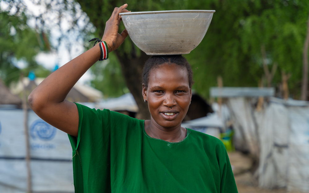 Mary Nyanhial Kiel, 34, arrives home in Lankien, balancing a bowl on her head as she prepares to cook an evening meal for her family | Date taken: 28/08/2024 | Photographer: Isaac Buay