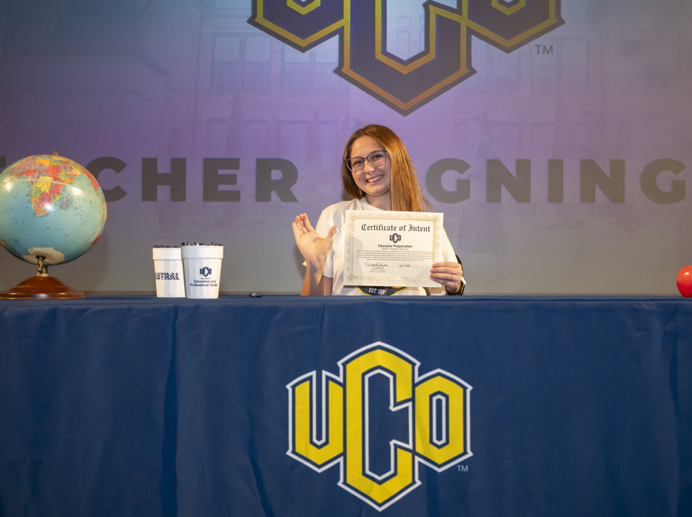 A student signs their certificate at UCO's Teacher Signing Day event.