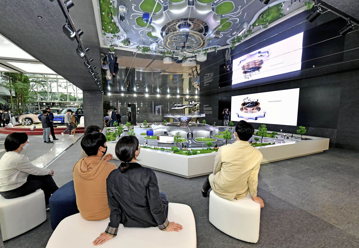 Los empleados de Hyundai Motor ven un modelo en miniatura de soluciones de movilidad inteligente, que incluye UAM, PBV y Hub, para un concepto dinámico de ciudad futura centrada en el ser humano, que se muestra en el vestíbulo del primer piso de su sede.