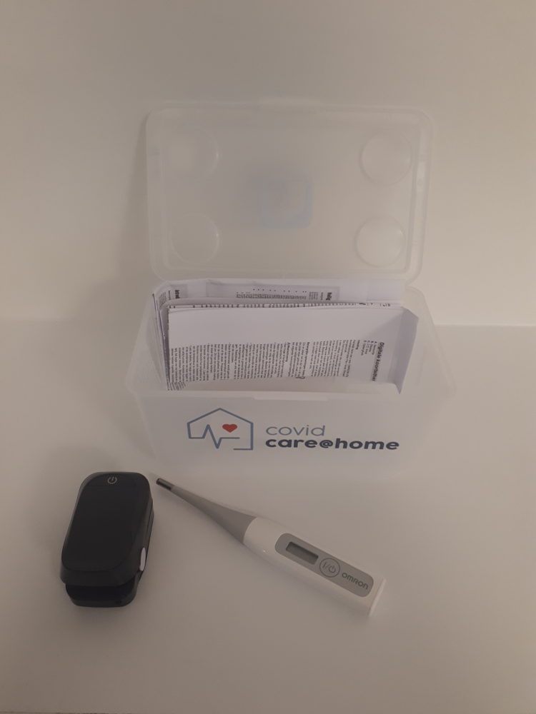 De box van CovidCare@home met een saturatiemeter en thermometer.