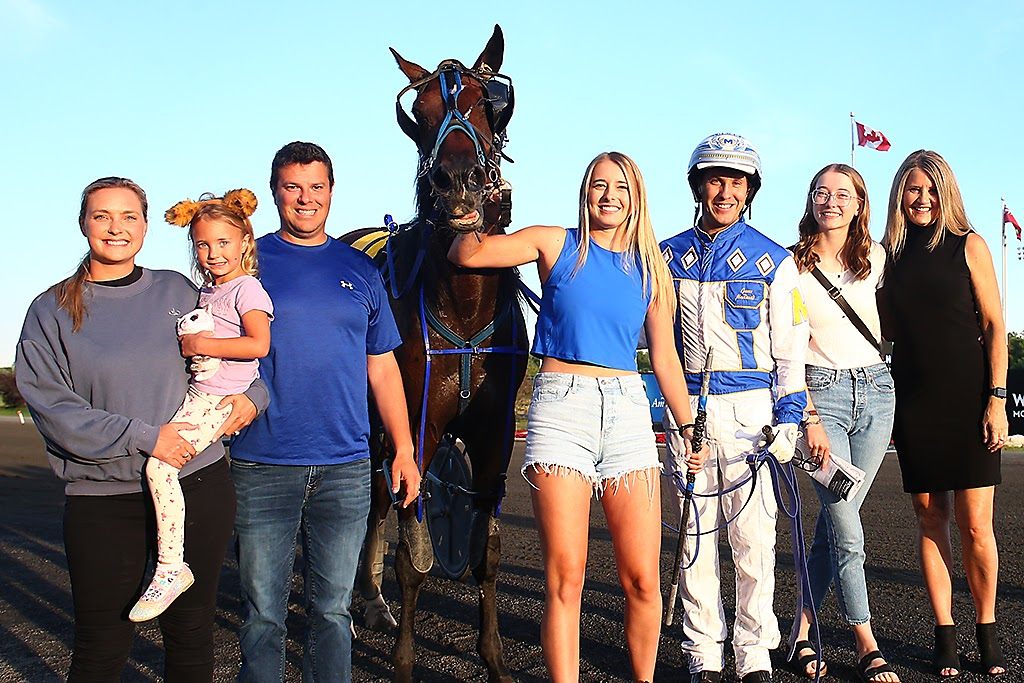 Paige Austin and James MacDonald pose with Hasty Bid and family in the winner's circle on August 27, 2022 (New Image Media)