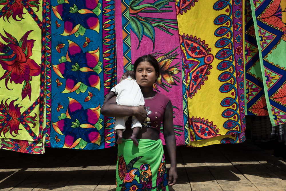 Nancy Arce (19-years-old) holds her son in her arms. Her partner, who was part of the Indigenous guard (civilian protection group) in Puesto Indio, was murdered months before the birth of the child. The family and wider community continue to fight to preserve his memory and to resist. Indigenous community of Puesto Indio, Alto Baudó, Chocó.