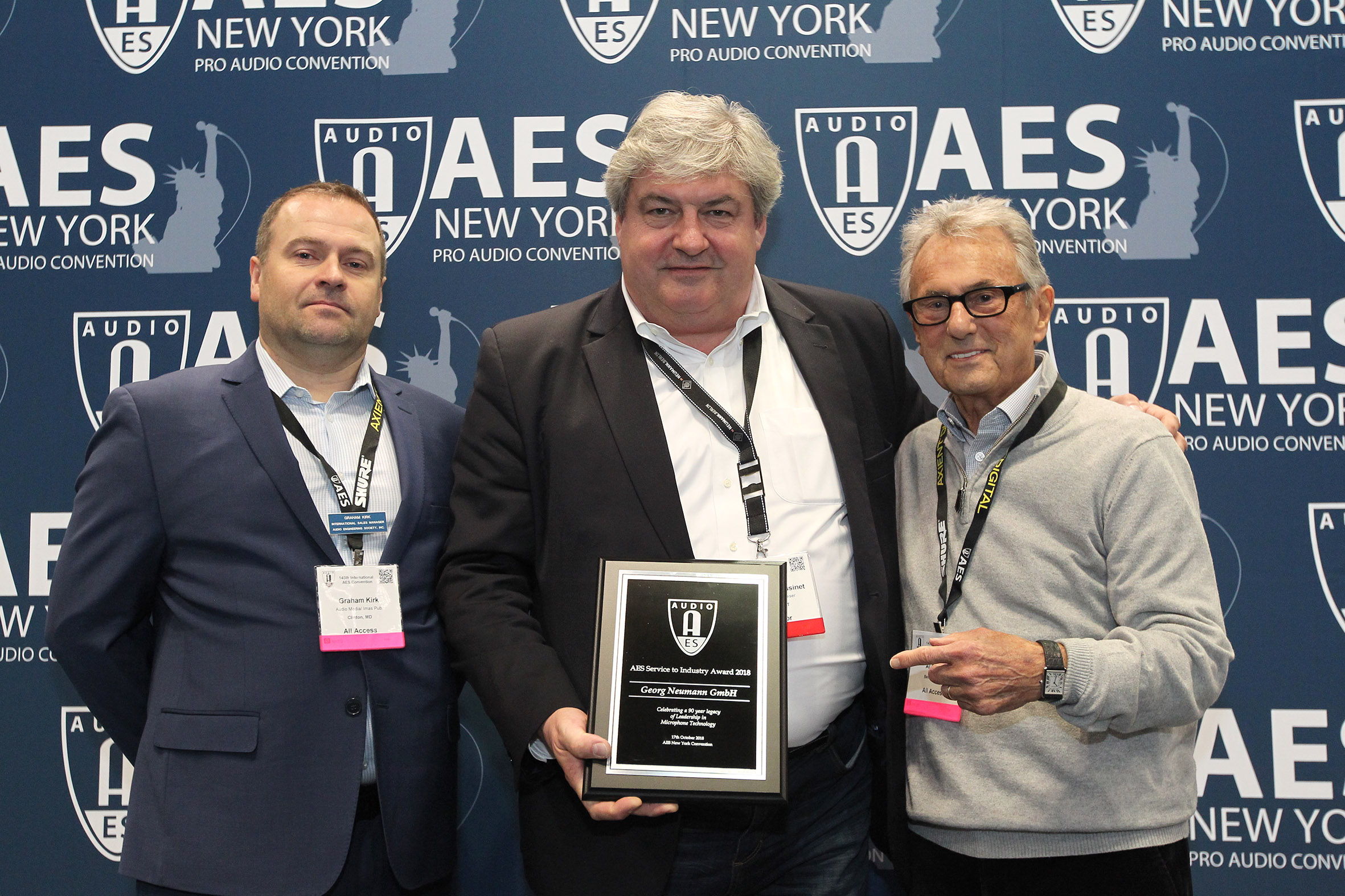 AES international sales director Graham Kirk (left) and multi-Grammy Award winning engineer/mixer Al Schmitt (right) present the award to Neumann president Wolfgang Fraissinet (center)